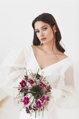 Portrait of elegant beautiful bride with unusual bouquet of flowers. Perfect makeup and hairstyle
