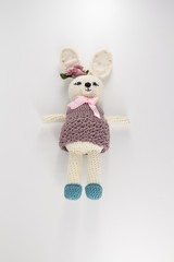 knitted toy rabbit in a sweater-dress with a flower on the ear on a white background