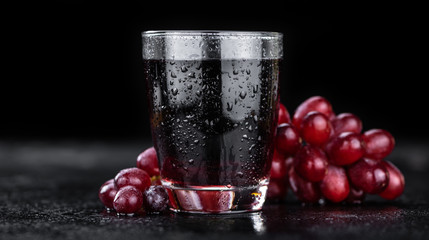 Fresh made Red Grape Juice on a slate slab (close-up shot; selective focus)