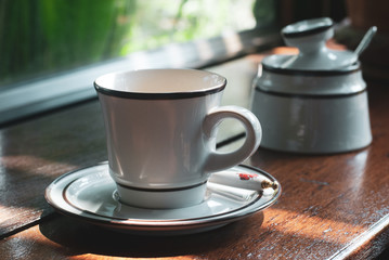 White ceramic coffee cup on the plate is placed on the wooden table in coffee cafe
