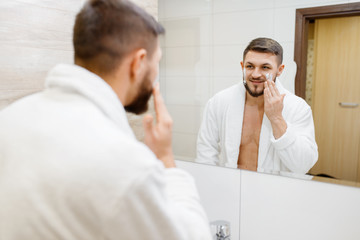 Obraz premium Man applies shaving foam, morning hygiene