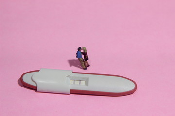 illustation photo for Lovely moment, Young Couple Mini figure Toy kissing beyond Pregnancy test pack with positive result