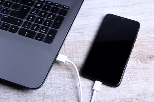 Plug In USB Cord,cable Charger,charging,charged And Data Transfer Of The Mobile Phone,smartphone With A Laptop On Wooden Floor,table Top View