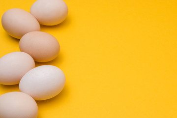 natural ecological eggs on yellow background in a row with copyspace