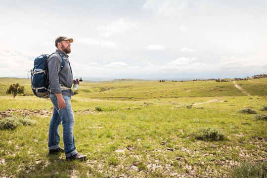 Bearded man hinking in rural prairie landscape. Cody, Wyoming, USA
