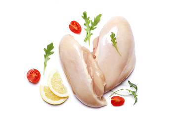 raw chicken fillet with tomato, lemon and arugula isolated on a white background