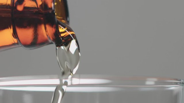 Slow motion closeup beer pour in glass from brown bottle