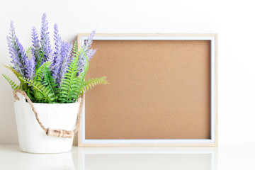 Frame mock up and plants in a vase on on the table. White colors. Greeting card. Background with copy space.