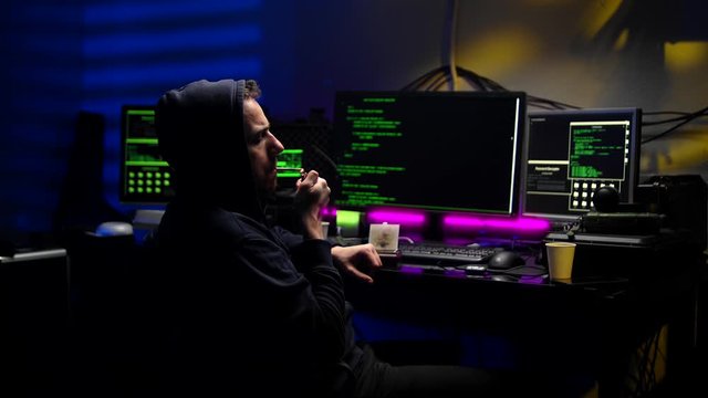 Man hacker rolling tobacco in dark room