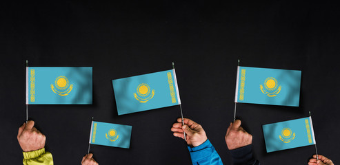 Hands holds flags of Kazakhstan on dark background