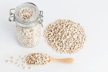 Heap of Job's tears or Coix lacryma-jobi a lot of with copy space for text isolated on white table background. Job's tears in the wooden spoon and in the glass bottle. Concept food for healthy.