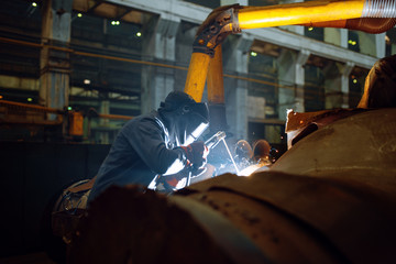 Welder in mask works with metal pipe on factory © Nomad_Soul