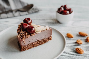 Cherry cake with nuts on a gray wooden background. Almonds in a raw dessert.