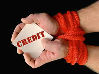 Hands tied with a rope, on a black background. Tied hands are holding a note with the inscription....