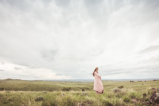 Young woman wrapped in blanket in a rural prairie setting. Cody, Wyoming, USA