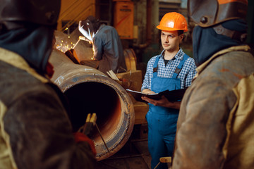 Master and crew of welders works on factory