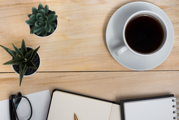 Workplace student. Business. Freelance. Diary, notebook, glasses, cup of coffee and plants on a wooden table.