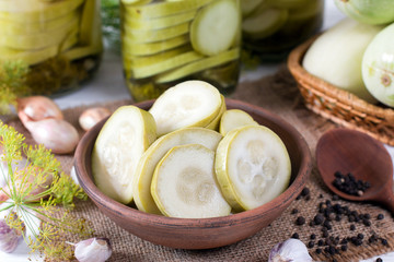 Pickled zucchini in glass jar on a wooden table