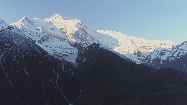 Aerial fly to Annapurna II snow giant mountain above dark forest slopes