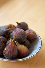 Ripe purple figs in dish on table
