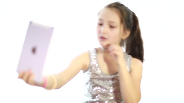 Cute little girl in front of the camera tablet. Girl shooting a video. Children's blog. Teen blogger. stream video for blog. Children's channel. Popular applications for success and popularity