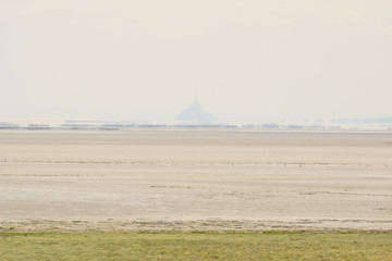 Le Mont Saint Michel en filigrane et La plage de la Baie du Mont Saint Michel et l'horizon de l'Océan Atlantique et de la Manche entre la  Bretagne et la Normandie