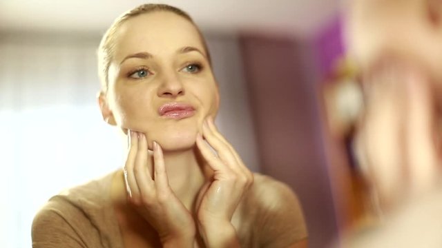 girl looks in the mirror, not pleased with the appearance, pulls the skin. Ugly, aging skin. Allergic to cosmetics, fear of aging, under eye circles, wrinkles. Low self-esteem, dysmorphic disorder. 