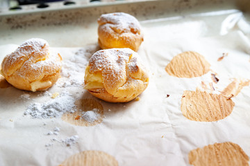 Homemade cakes. Freshly baked hot sweet buns sprinkled with powdered sugar and stacked on baking paper on a baking sheet.