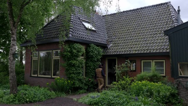 A property surveyor is seen entering a house to complete a survey of the house from inside and outside. A surveyor busy viewing a farmhouse property in the Netherlands.