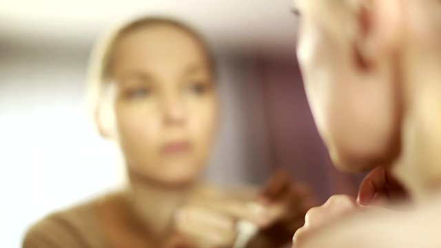 girl looks in the mirror, not pleased with the appearance, pulls the skin. Ugly, aging skin. Allergic to cosmetics, fear of aging, under eye circles, wrinkles. Low self-esteem, dysmorphic disorder. 