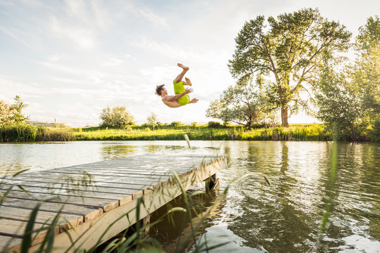 Young guy having fun in a swimming lake jumping off dock. Bridger, Montana, USA