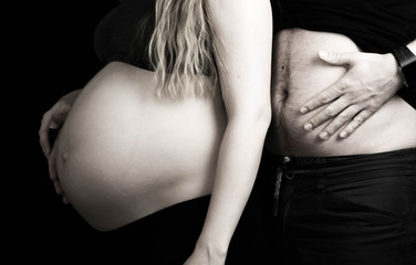 Funny pregnant couple, daddy compares his belly to his wife's pregnant stomach, expecting baby together.