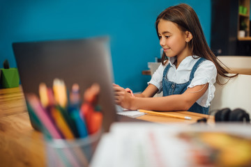 Cheerful young little girl children using laptop computer, studying through online e-learning...