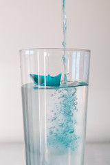 Blue paper boat in a glass of water