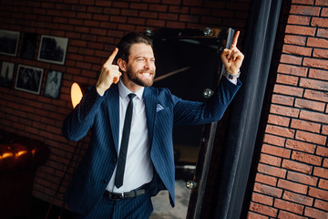 Portrait of very excited bearded businessman, celebrating victory with raised hands and screaming.