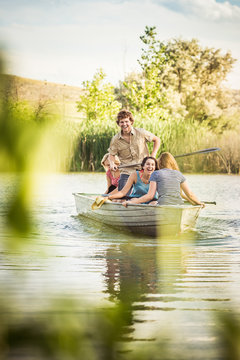 Group of young adults having fun in a swimming lake while rowing a boat. Bridger, Montana, USA