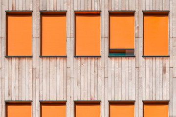 Vertical wood cladding exterior with bright orange roller blinds. Modern facade detail with flat windows. Minimal aesthetics. High resolution architecture photography.