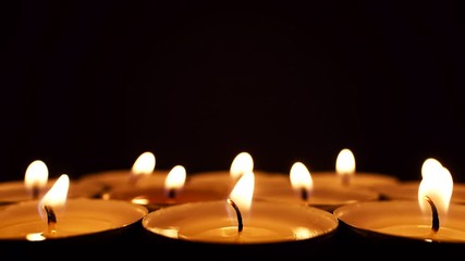 Burning candles in a row in the dark close up