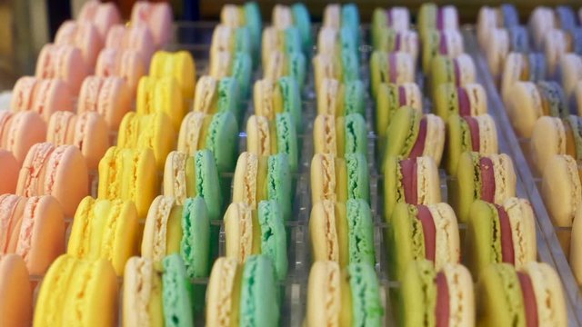 Close Up Colorful Macarons Dessert in Bakery Shop at Store Glass Case. Closeup French Deserts Lying at Cafe