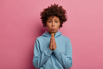 I beg you, please. Pitty curly girl looks with imploring face, pleads desperately, keeps palms...