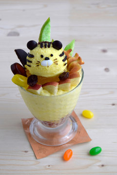 Ice cream is made in form of tiger. Creative dessert for children. Dessert contains apple, cookies, candy, papaya