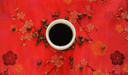 China specialty coffee concept. Black coffee in white cup on red traditional chinese pattern...