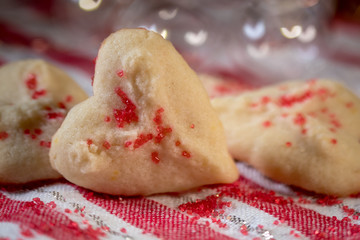 Heart shaped butter spritz cookies with red sugar sprinkles closeup heart bokeh selective focus