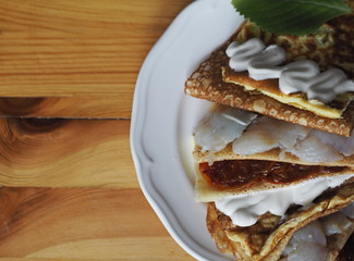 Pancakes stuffed with fish, scrambled eggs, tomatoes on a dark kitchen cutting board. A stack of pancakes. Background for Shrovetide.