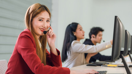 Beautiful young woman in headphones with microphone consulting client on phone in customer support service