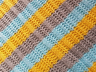 Striped sweater background. Blue, gray, yellow knitted stripes.
