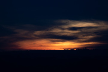 A distant silhouette of a tree line in front of a dramatic sunrise