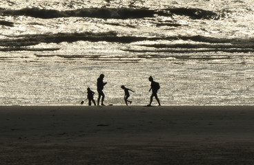 Fototapeta na wymiar Famille qui joue sur plage
