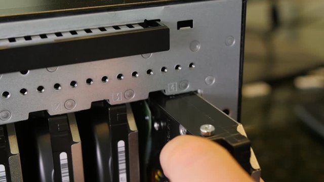 Editorial: HEBER, UT, UNITED STATES, FEBRUARY 10, 2020: Attaching hard disc to the back of PC case. Hand held close up video as man teaches to insert HDD to the back of PC tower.