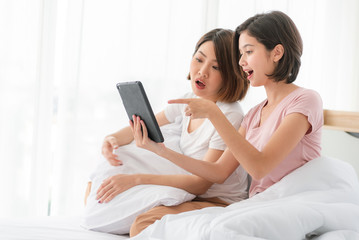 Two girls using laptop together on a bed in living room